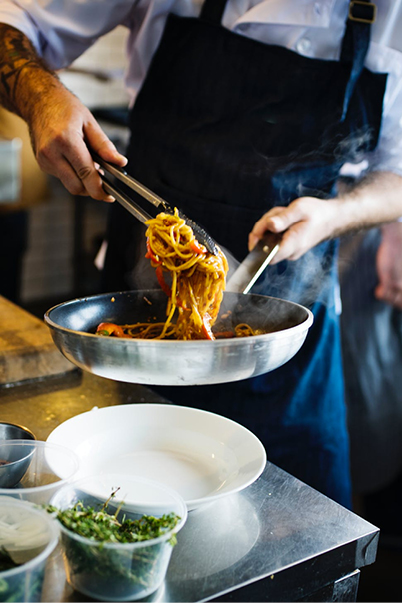 Mann bruker en klype for å legge spaghetti på en asjett