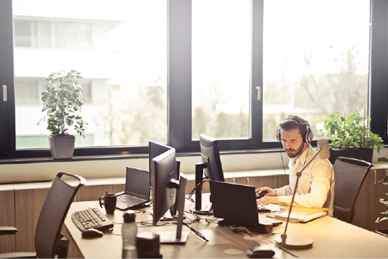 Mann jobber på datamaskin med headset på